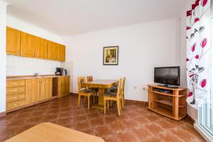 a kitchen with a dining room table and a television at Apartments Bozana in Zaton
