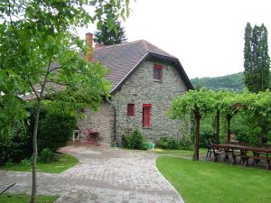 a stone house with red windows and a brick walkway at Gereben Villa in Velem