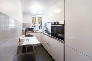 una cucina con mobili bianchi, tavolo e sedie di Elegant Apartment with Stunning Lake View a Montreux