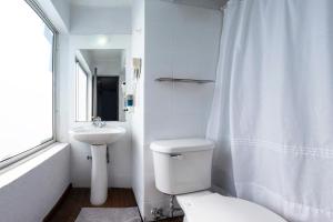 Baño blanco con aseo y lavamanos en Etnico Bío Bío Hotel, en Los Ángeles