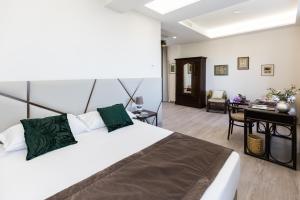 a bedroom with a large white bed and a desk at Villa Cavalletti Appartamenti in Grottaferrata
