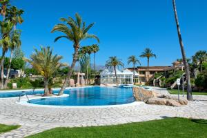 une piscine bordée de palmiers et une maison dans l'établissement Camping Villasol, à Benidorm