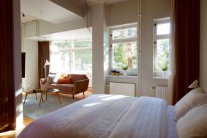 um quarto com uma cama, uma cadeira e janelas em Second Home Apartments Asplund em Solna