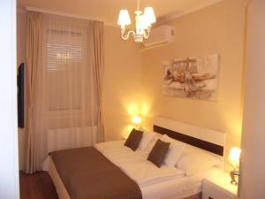 1 dormitorio con 1 cama con sábanas blancas y ventana en Ametiszt Apartman, en Hévíz