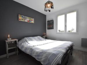 a bedroom with a bed and a chandelier and two windows at Holiday home near the beach in Agon-Coutainville