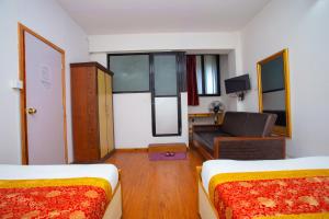 a room with two beds and a living room with a couch at The Boudha Inn in Kathmandu