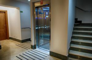 un corridoio con ascensore in vetro in un edificio di Le Petit León a León