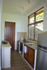 a kitchen with a sink and a refrigerator at La Perle Appartements in Baie Lazare Mahé