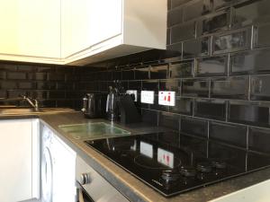 eine Küche mit einer schwarz gefliesten Wand in der Unterkunft Fishergate ApartHotel 2 - City Centre Location in Preston