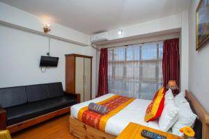 a bedroom with a bed and a couch and a window at The Boudha Inn in Kathmandu