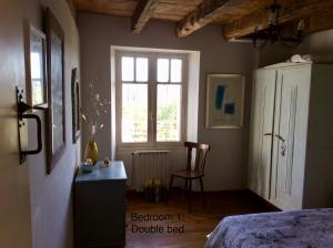 a bedroom with a bed and a window and a chair at Les Outres in Chabrac