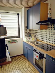 a kitchen with blue cabinets and a sink and a window at Ferienwohnung Prange Cuxhaven in Cuxhaven