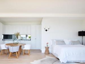 a bedroom with a bed and a table and a kitchen at THE CAPE at Wategos - Lodging in Paradise in Byron Bay