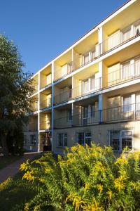 an apartment building with yellow flowers in the foreground at Ośrodek Wypoczynkowy Ania Dźwirzyno in Dźwirzyno