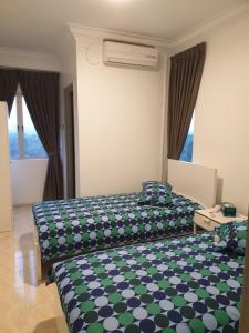 two beds in a hotel room with green at 5-Bedroom Family Apartment in Seri Kembangan