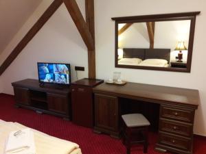 Hotel Fogl في نوفا بيستويس: غرفة نوم مع مرآة ومكتب مع تلفزيون