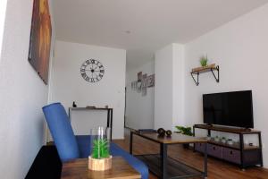 a living room with a blue chair and a tv at Sweet Park Appartements in Rheinhausen