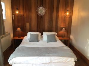 una camera da letto con un grande letto bianco con due lampade di Le Pavillon Bleu a Cap-Ferret