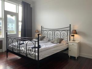 a bedroom with a black bed with a nightstand and a window at Downtown Guesthouse Reykjavik in Reykjavík