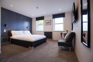 una camera d'albergo con letto e sedia di Asperion Hotel a Guildford