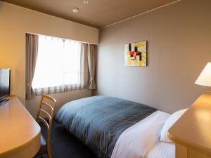 a hotel room with a bed and a desk and a window at Himeji Castle Grandvrio Hotel in Himeji