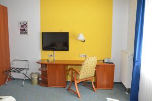 um quarto com uma secretária, uma televisão e uma cadeira em Central Inn Hotel garni em Eppelborn