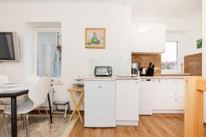 a kitchen with white cabinets and a table and chairs at Cozy Apartments by Renters in Świnoujście