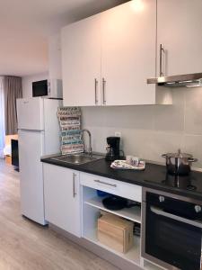 a kitchen with white cabinets and a black counter top at Residencia Beach in Cambrils