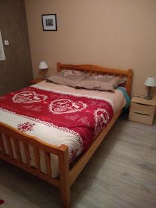 SelonnetにあるLes logis de Lucieのベッドルーム1室(木製ベッド1台、赤と白の毛布付)