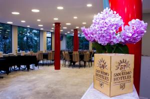 a room with a table with purple flowers in a box at San Remo Viking Hotel in Pinamar