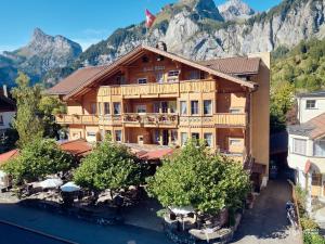 un gran edificio de madera con una montaña en el fondo en Chalet Hotel Adler AG, en Kandersteg