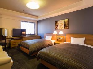 a hotel room with two beds and a flat screen tv at Himeji Castle Grandvrio Hotel in Himeji