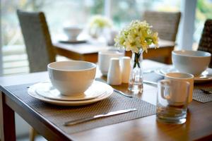 a table with two cups and a vase of flowers at Borthwenbnb in Dolgellau