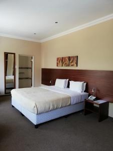 a bedroom with a large bed with a wooden headboard at The Shakespeare Inn in Vanderbijlpark