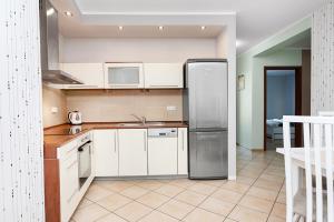 シュチェチンにあるSAS Apartamenty New Parkのキッチン(白いキャビネット、ステンレス製の冷蔵庫付)