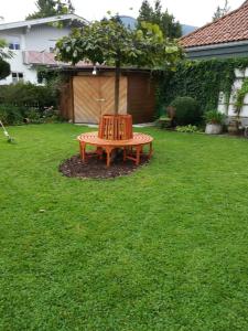 een houten bank in een tuin met een boom bij Haus Pierzinger in Wörgl