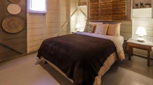 a bedroom with a bed and a table and two lamps at La Bicok EcoLodge in Mindo