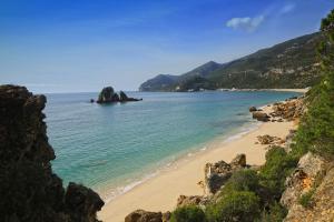 a beach with a rock formation in the water at RM The Experience - Small Portuguese Hotels in Setúbal