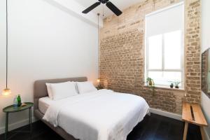 um quarto com uma cama branca e uma parede de tijolos em Oliver em Tel Aviv