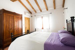 a bedroom with a large bed and a wooden cabinet at Case Vacanze S'Arrexina in Rudalza