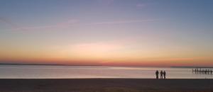 zwei Personen stehen bei Sonnenuntergang am Strand. in der Unterkunft River Edge Inn in Colonial Beach