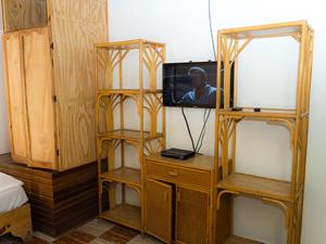 um quarto com televisão e duas prateleiras de madeira em Plaza Real Resort em Juan Dolio