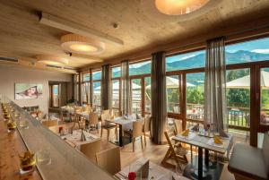 un restaurante con mesas, sillas y ventanas grandes en Familienresort & Kinderhotel Ramsi en Hermagor