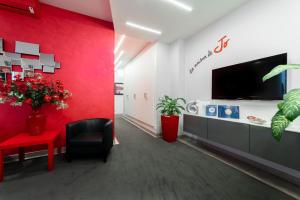 une salle d'attente avec un mur rouge et une télévision dans l'établissement B&B La Maison de Jo, à Rome