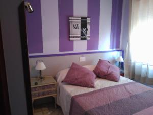 - une chambre avec des murs violets et un lit avec des oreillers violets dans l'établissement HOSTAL RESTAURANTE MILAN II, à San Clemente