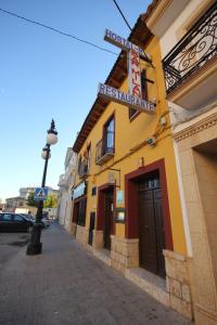 un bâtiment avec un panneau indiquant un restaurant dans une rue dans l'établissement HOSTAL RESTAURANTE MILAN II, à San Clemente