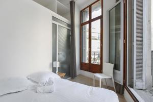 a white bedroom with a bed and a window at Comédie Lonjon in Montpellier