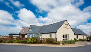 a white building with a black roof on a street at Sessile Oak, Llanelli by Marston's Inns in Llanelli