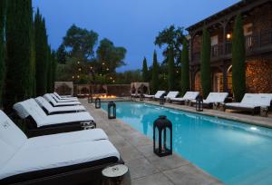 a swimming pool with white lounge chairs next to a building at Hotel Yountville in Yountville