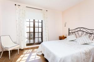1 dormitorio con 1 cama, 1 silla y 1 ventana en Home2Book El Médano Cozy Beach & Wifi en El Médano